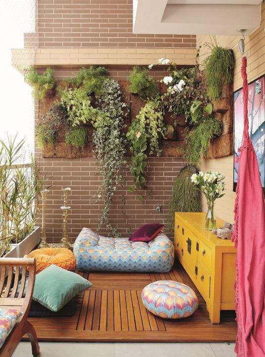 Varanda decorada com plantas, móveis coloridos e almofadas.