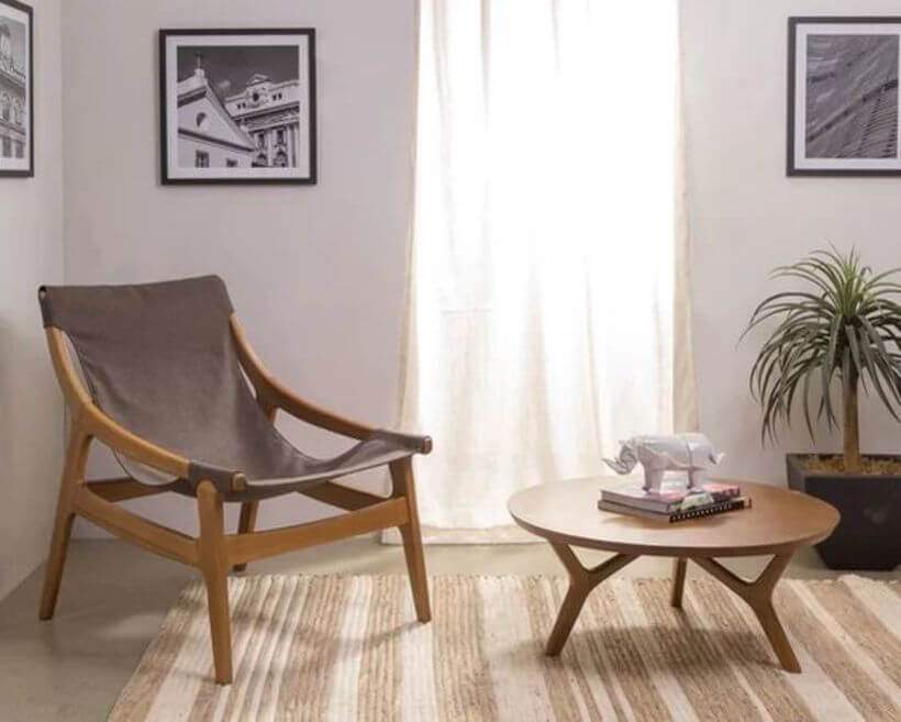 Móveis de madeira (Poltrona Bertini), tapete de fibra e vaso de planta compõem este canto de leitura com ar campestre. Foto: Oppa.